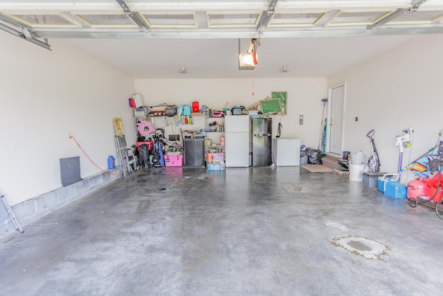 garage with freestanding refrigerator, refrigerator, and a garage door opener