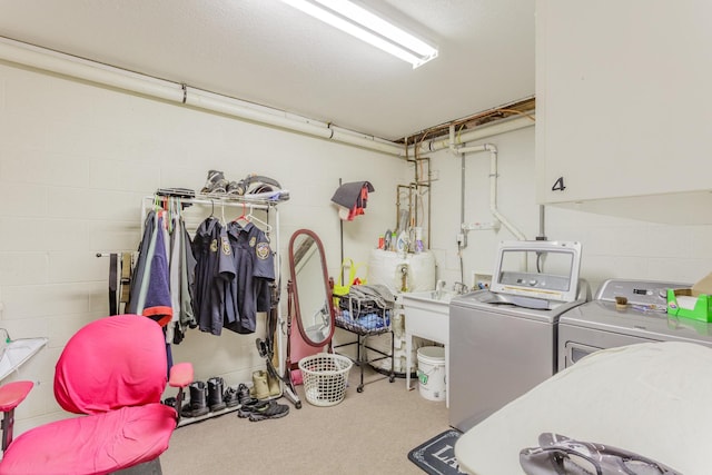 laundry area featuring cabinet space, concrete block wall, carpet floors, a sink, and separate washer and dryer