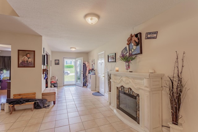 entrance foyer featuring a glass covered fireplace, a textured ceiling, and light tile patterned flooring