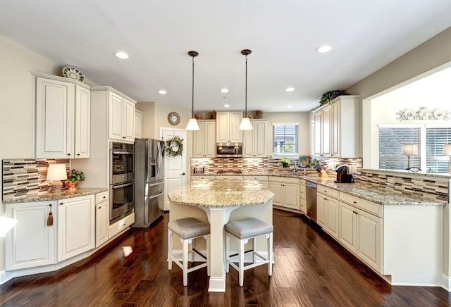5028 Rockport Ave, Franklin, TN 37064 - kitchen with appliances with stainless steel finishes, a kitchen breakfast bar, decorative backsplash, and light stone countertops