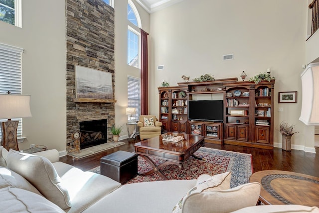 5028 Rockport Ave, Franklin, TN 37064 - living area featuring dark wood-style flooring, a stone fireplace, visible vents, a towering ceiling, and baseboards