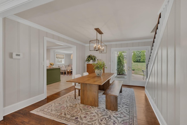 dining room with french doors, ornamental molding, a decorative wall, and a chandelier