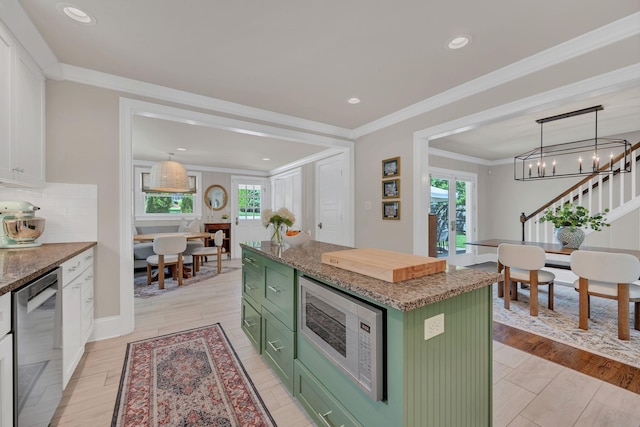 kitchen featuring plenty of natural light, appliances with stainless steel finishes, green cabinetry, and crown molding
