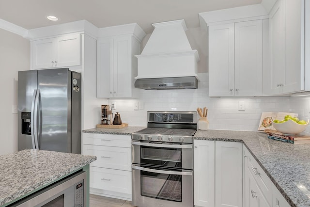 kitchen with appliances with stainless steel finishes, custom exhaust hood, recessed lighting, and white cabinetry