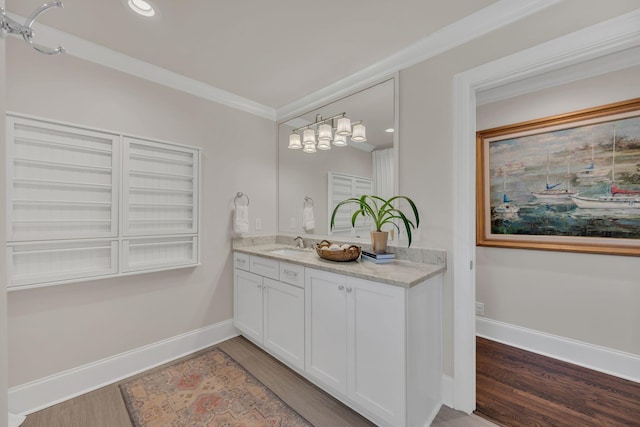 bathroom featuring crown molding, baseboards, wood finished floors, and vanity
