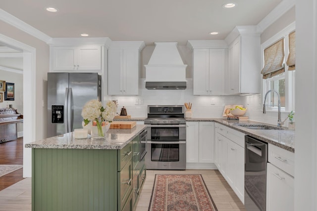 kitchen with backsplash, appliances with stainless steel finishes, a sink, custom range hood, and white cabinetry