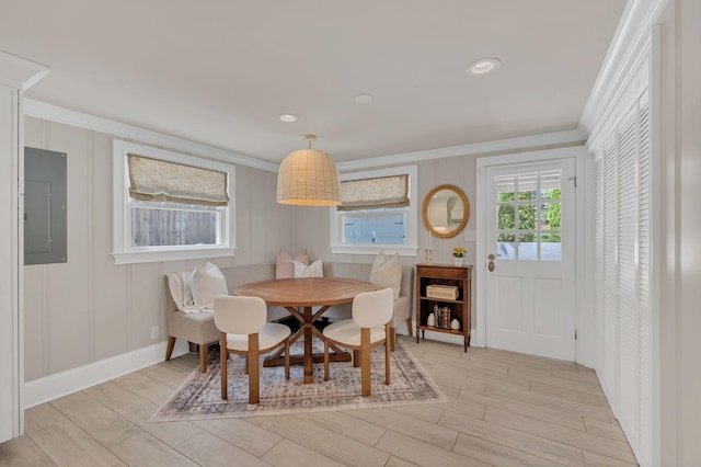 dining room with crown molding, electric panel, and light wood finished floors