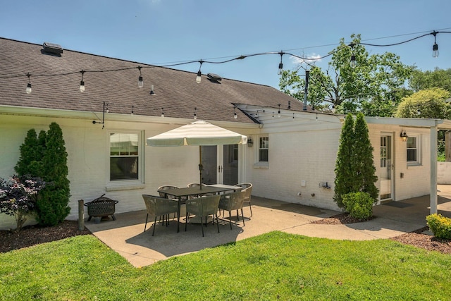 back of property featuring roof with shingles, a patio area, and brick siding