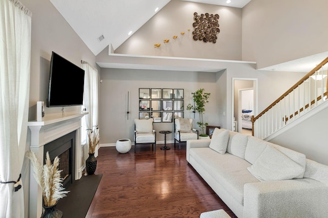 living room with a fireplace, high vaulted ceiling, dark wood finished floors, visible vents, and stairway