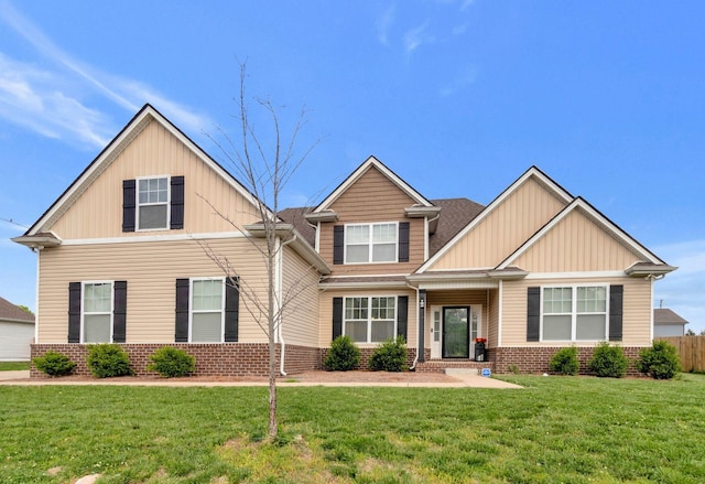 craftsman house with brick siding, a front lawn, board and batten siding, and fence