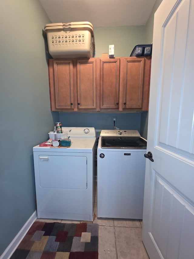 washroom featuring cabinet space, light tile patterned floors, and washer and dryer