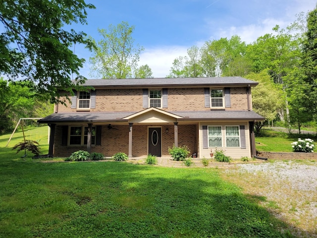 traditional-style home featuring a ceiling fan, brick siding, and a front yard