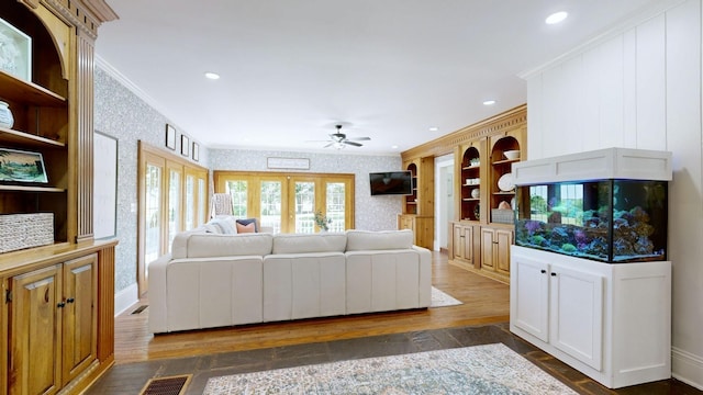 living area with ornamental molding, ceiling fan, dark wood-style floors, and wallpapered walls