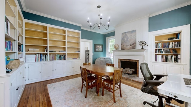 dining area featuring an inviting chandelier, a brick fireplace, wood-type flooring, built in features, and ornamental molding