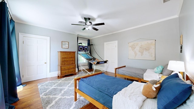 bedroom with ornamental molding, ceiling fan, and wood finished floors