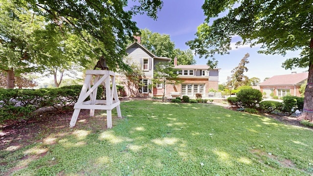 exterior space featuring a chimney, a yard, and brick siding