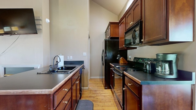 kitchen featuring dark countertops, a sink, light wood finished floors, vaulted ceiling, and black appliances