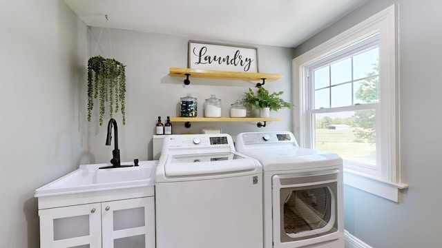 clothes washing area with cabinet space, washing machine and dryer, and a sink