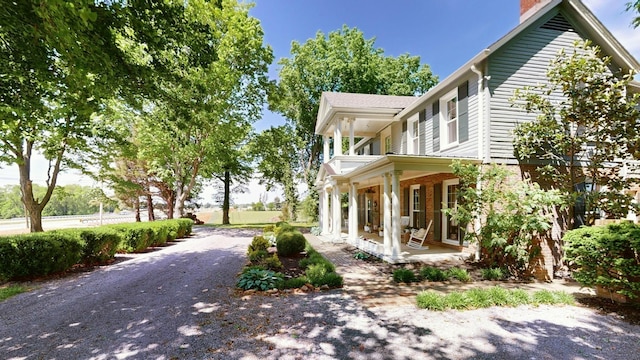 view of side of home featuring a chimney and a porch