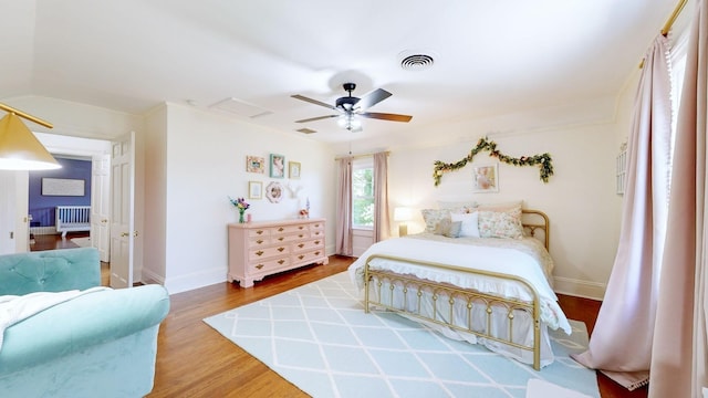 bedroom with baseboards, a ceiling fan, wood finished floors, and visible vents