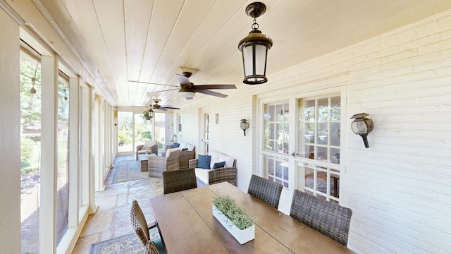 sunroom featuring a ceiling fan, an outdoor living space, and a wealth of natural light