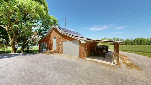 view of side of home featuring dirt driveway, solar panels, and brick siding