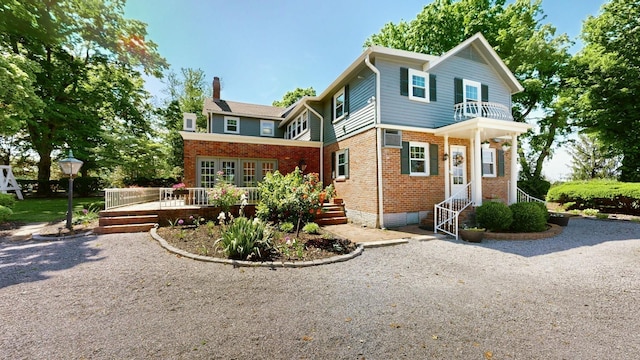 view of front of home featuring brick siding, a deck, crawl space, a chimney, and a balcony