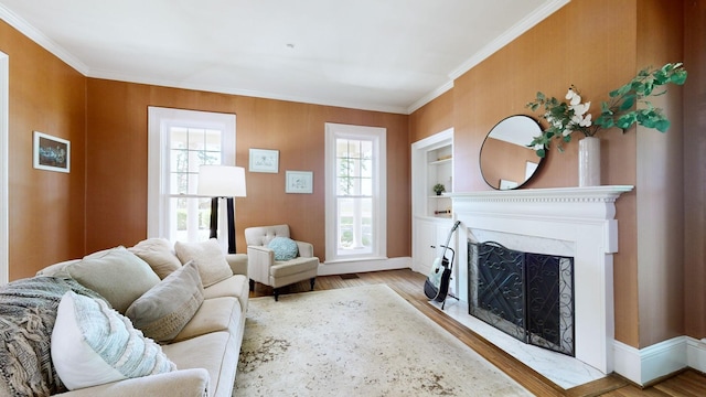 living room with a premium fireplace, built in features, baseboards, wood finished floors, and ornamental molding