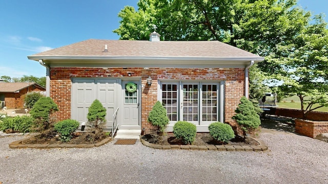 exterior space with roof with shingles, a chimney, and brick siding