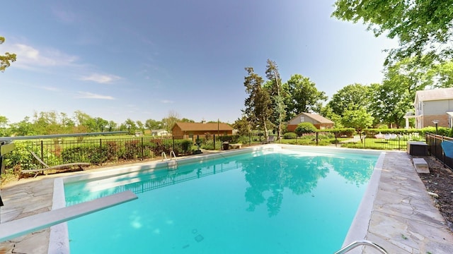 view of swimming pool with fence, a fenced in pool, and a diving board