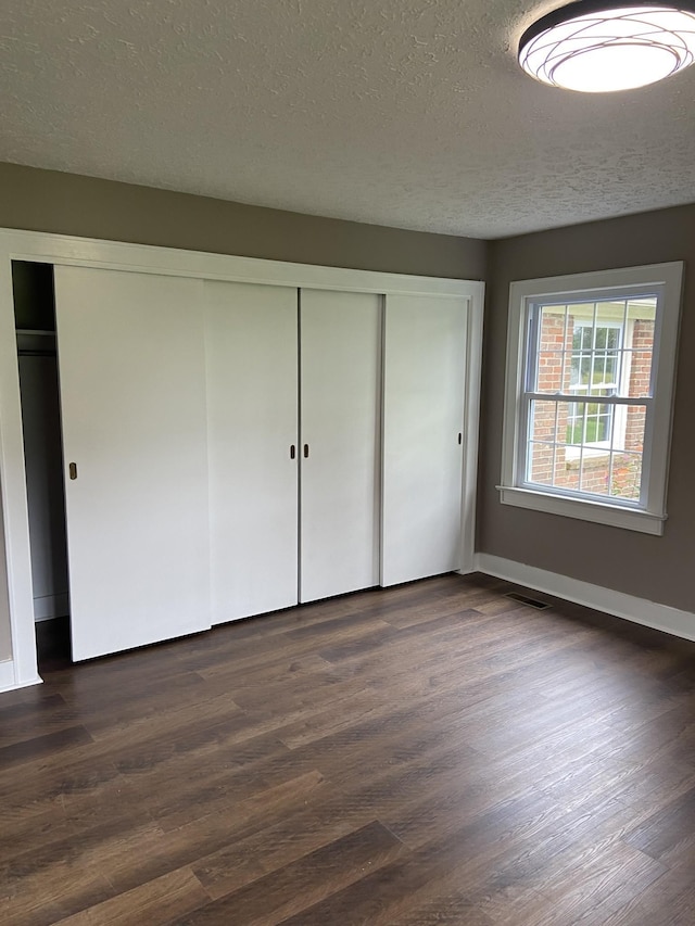 11495 Guthrie Rd, Guthrie, KY 42234 - unfurnished bedroom featuring a textured ceiling, dark wood-style floors, baseboards, and a closet
