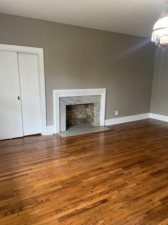 11495 Guthrie Rd, Guthrie, KY 42234 - unfurnished living room featuring baseboards, an inviting chandelier, hardwood / wood-style flooring, and a high end fireplace