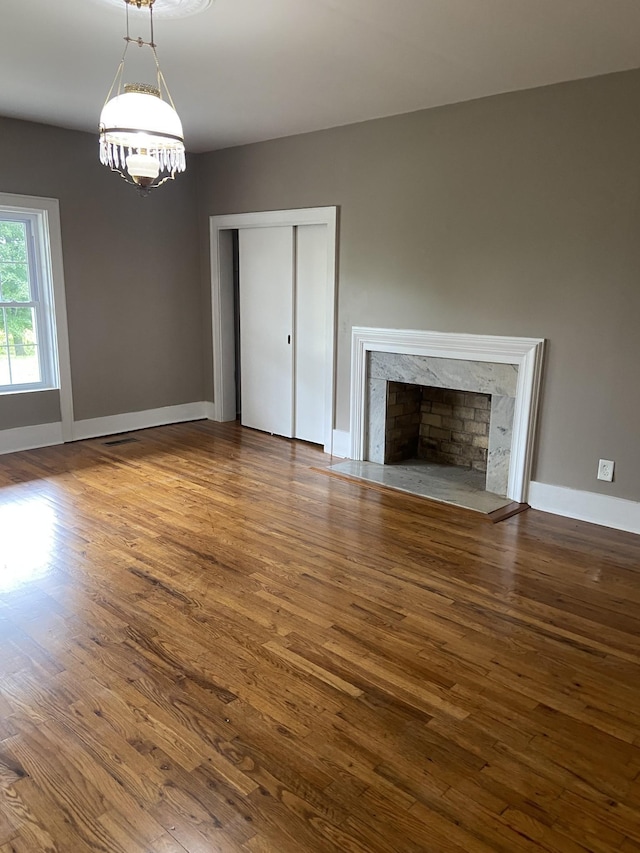 11495 Guthrie Rd, Guthrie, KY 42234 - unfurnished living room featuring baseboards, an inviting chandelier, wood finished floors, and a high end fireplace