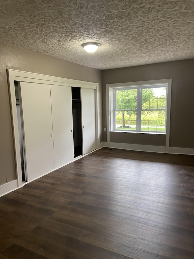 11495 Guthrie Rd, Guthrie, KY 42234 - unfurnished bedroom featuring a textured ceiling, baseboards, dark wood finished floors, and a closet