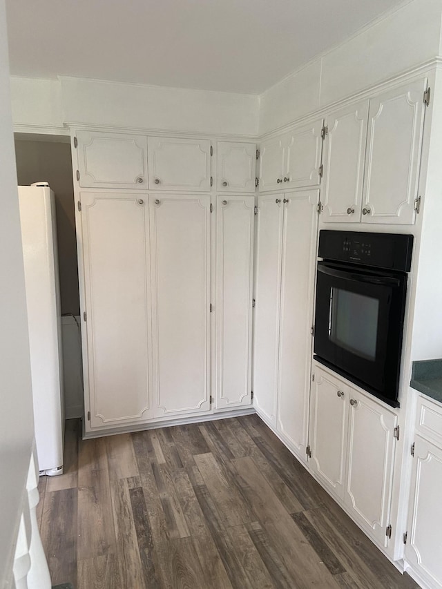 11495 Guthrie Rd, Guthrie, KY 42234 - kitchen featuring dark wood-type flooring, freestanding refrigerator, white cabinetry, and black oven