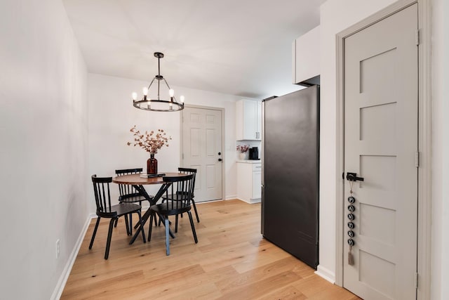 dining space with an inviting chandelier, light wood-style flooring, and baseboards