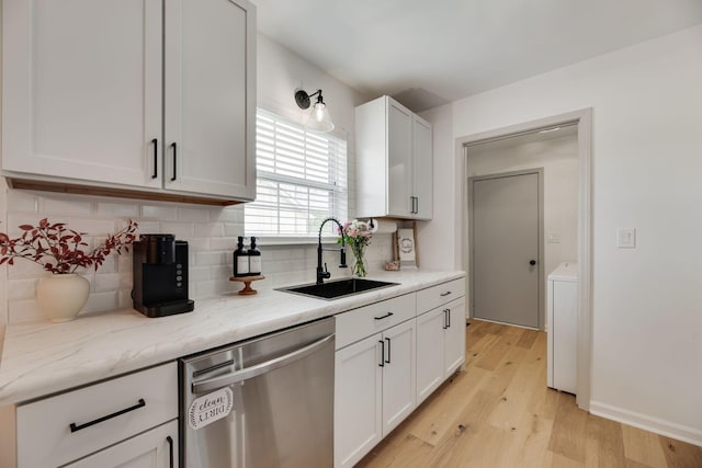 kitchen featuring a sink, dishwasher, light wood-style flooring, washer / dryer, and backsplash