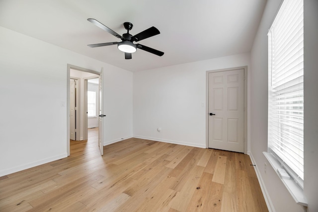 spare room with baseboards, light wood finished floors, and ceiling fan