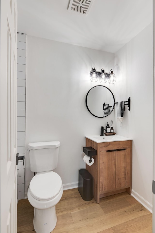 bathroom featuring visible vents, wood finished floors, baseboards, vanity, and toilet