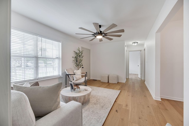 sitting room featuring baseboards, a ceiling fan, and light wood-style flooring