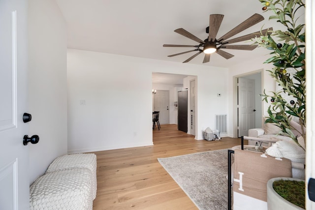 interior space featuring visible vents, a ceiling fan, light wood-style floors, and baseboards