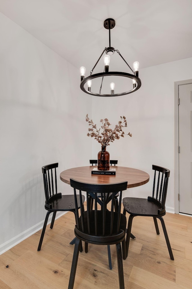 dining space featuring baseboards, light wood finished floors, and a notable chandelier