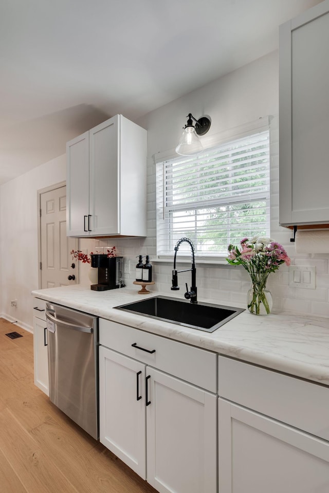kitchen with backsplash, light wood-style floors, a sink, and dishwasher