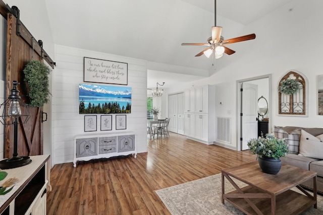 557 Skyview Dr, Ashland City, TN 37015 - living area featuring visible vents, a barn door, wood finished floors, high vaulted ceiling, and ceiling fan with notable chandelier