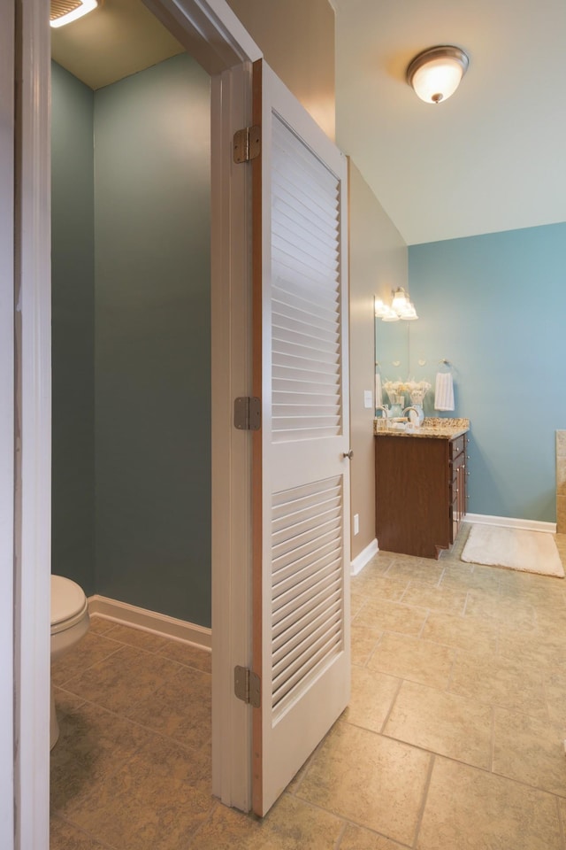 bathroom featuring toilet, baseboards, and vanity