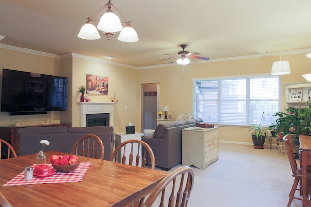 carpeted dining space with baseboards, ornamental molding, a fireplace, and a ceiling fan