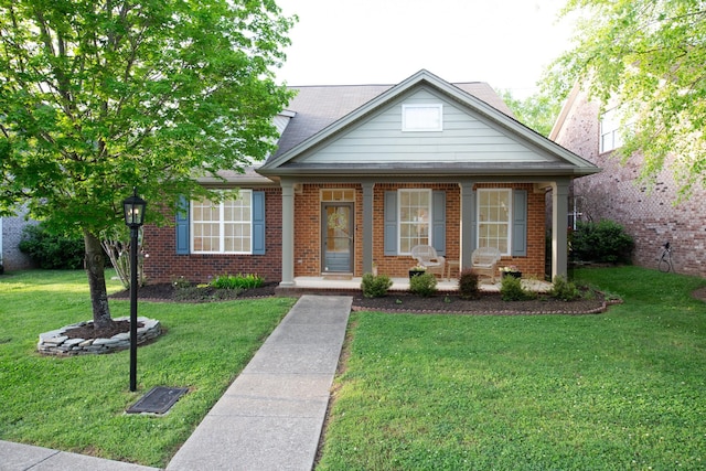 view of front facade featuring brick siding, covered porch, and a front yard