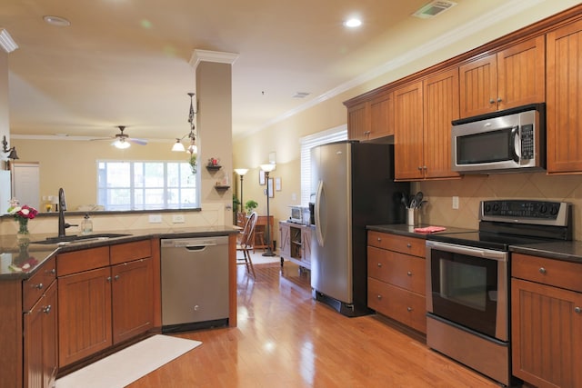 kitchen with brown cabinets, crown molding, appliances with stainless steel finishes, a sink, and visible vents
