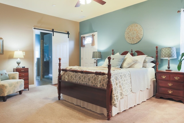 bedroom featuring ceiling fan, a barn door, and light colored carpet
