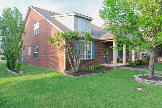 view of front of house with brick siding, a front lawn, and a porch